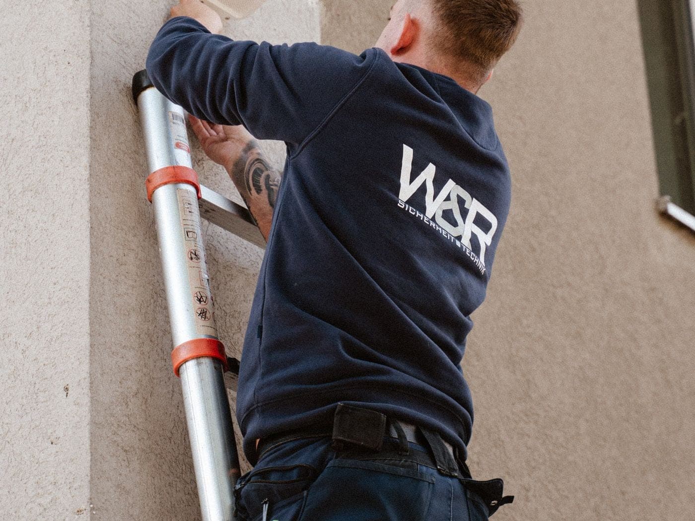Techniker von W&R Sicherheitstechnik im Markenpullover bei der Sirenen-Montage